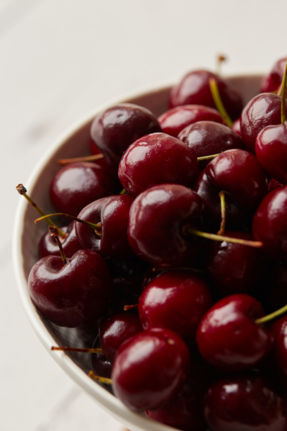 A bowl of fresh dark cherries on a pale table