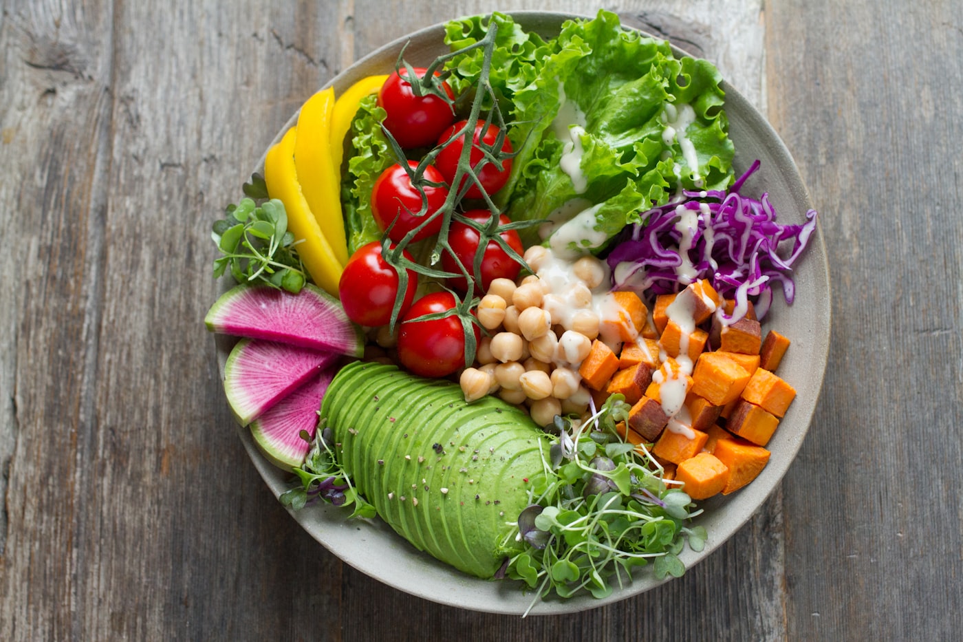 A colourful bowl of avocado, chickpeas, tomatoes, greens and sweet potato