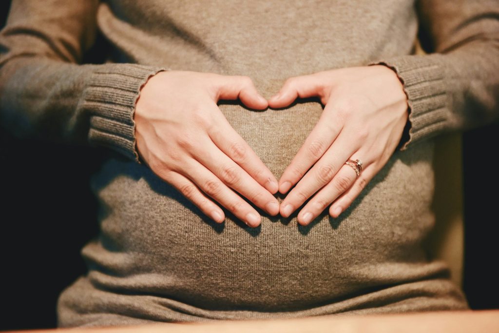 Hands forming a heart over a pregnant belly